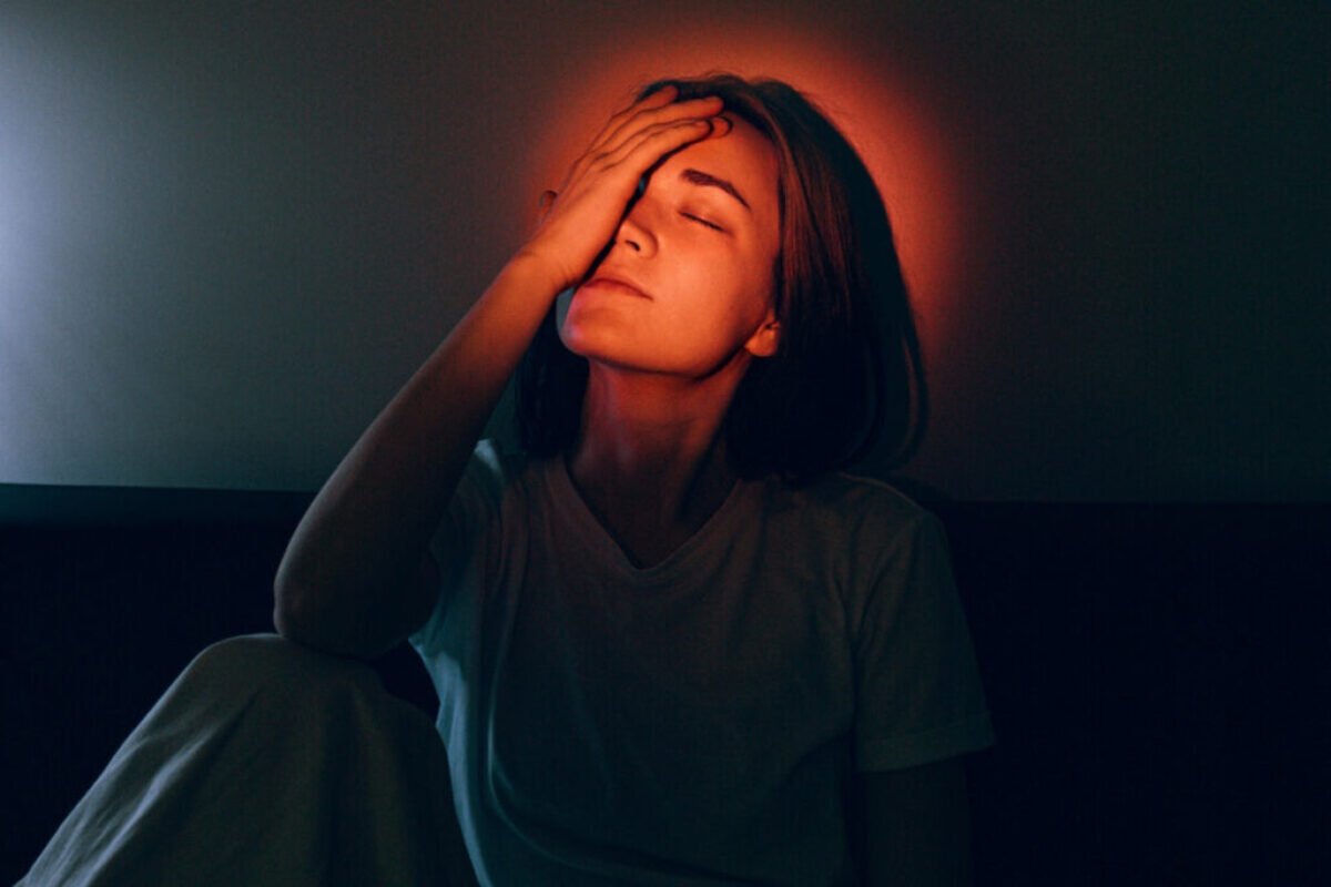 Woman with hand on forehead surrounded by a glowing light, symbolizing renewing the mind