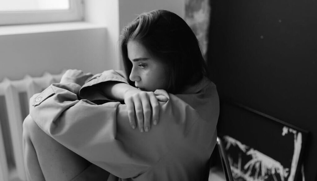 Somber woman sitting with her knees pulled in, representing the pressure and burden of Christian legalism