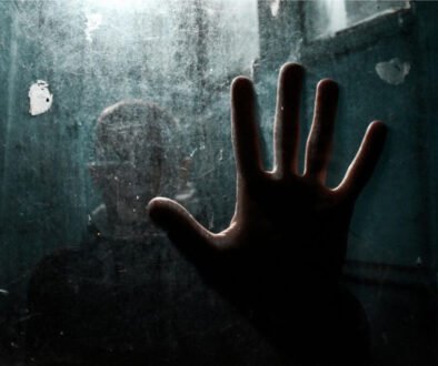 Person standing behind fogged glass with hand pressed against it, representing Elijah and depression and emotional isolation