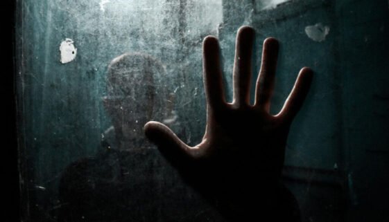 Person standing behind fogged glass with hand pressed against it, representing Elijah and depression and emotional isolation